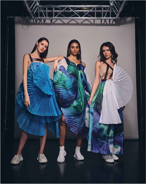 Three models wearing similar long, blue dresses. 
